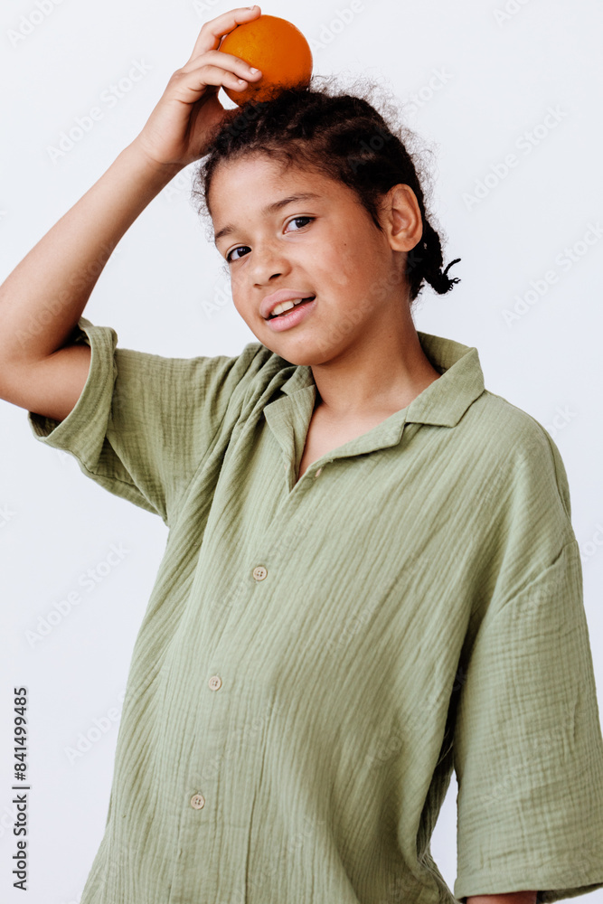 playful young boy holding orange above head against clean white background playful young boy holding orange above head against clean white background