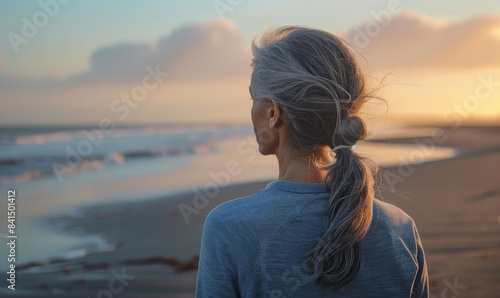 A woman with grey hair looking at the sea coastline