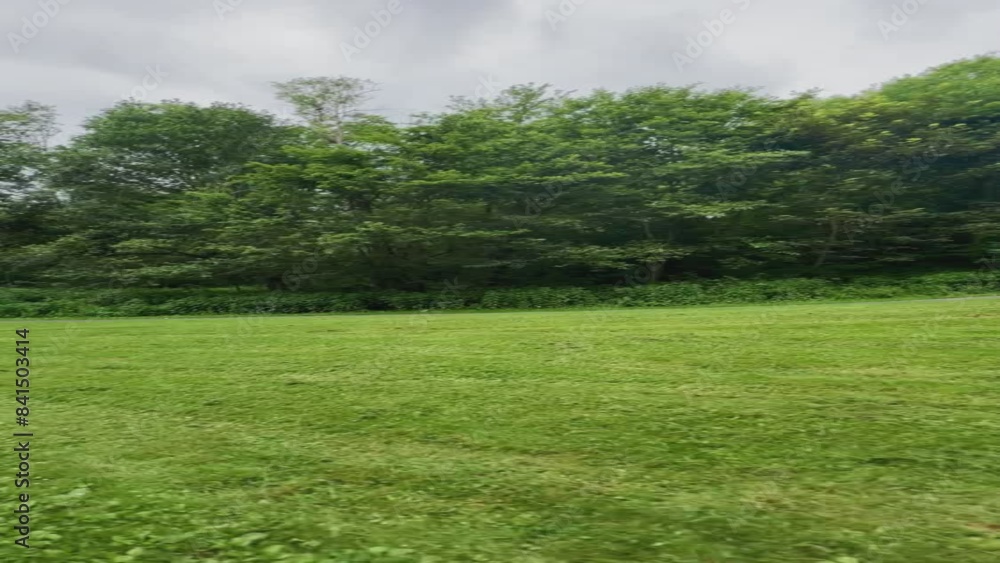 Walking past a small hill in a green park on a cloudy day Walking past a small hill in a green park on a cloudy day