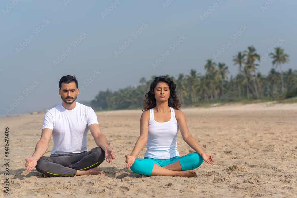 Man and woman doing yoga at the beach Man and woman doing yoga at the beach