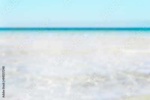 Bumpy tropical sandy beach with blurry transparent ocean and blue sky