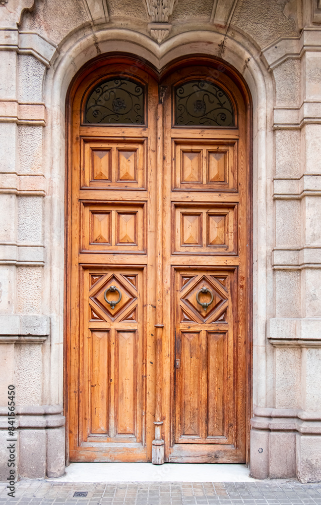 A wooden door with a handle in the wall of the house in close-up - Barcelona, Spain A wooden door with a handle in the wall of the house in close-up - Barcelona, Spain