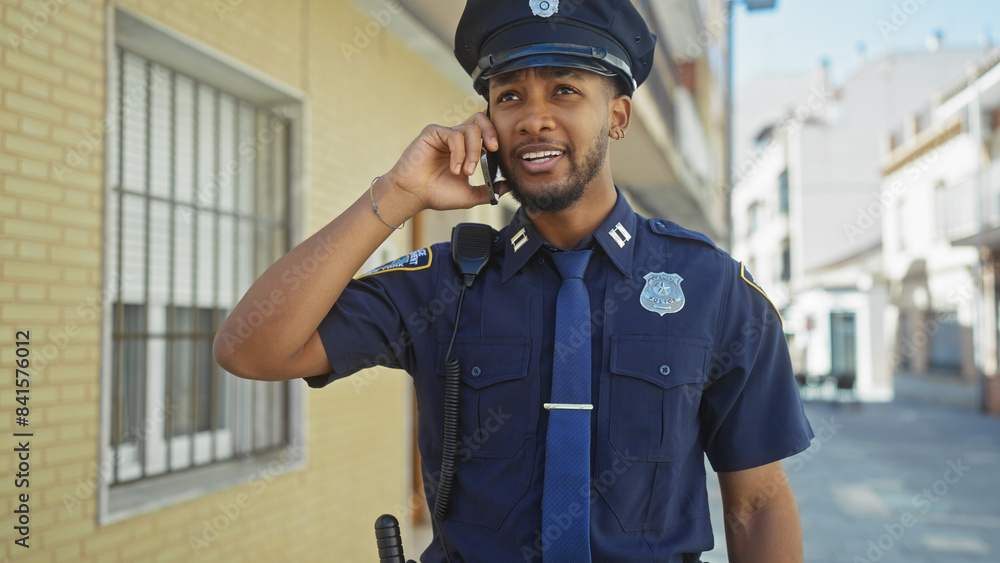 An african american police officer talking on his radio with a city street in the background. An african american police officer talking on his radio with a city street in the background.