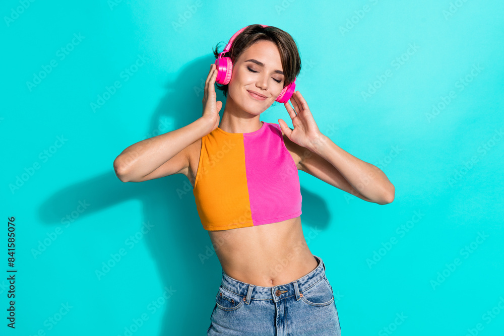 Photo of dreamy pretty woman wear pink orange top closed eyes enjoying music headphones isolated teal color background Photo of dreamy pretty woman wear pink orange top closed eyes enjoying music headphones isolated teal color background