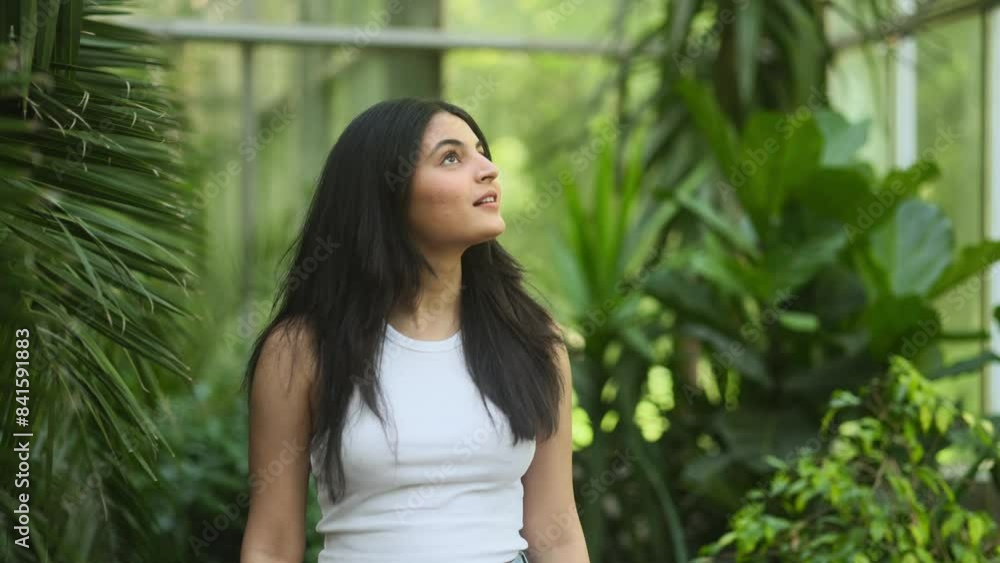Charming young indian woman with long hair looking around at green Botanical Garden indoors Happy relaxed tourist on greenhouse enjoying beautiful day alone Charming young indian woman with long hair looking around at green Botanical Garden indoors Happy relaxed tourist on greenhouse enjoying beautiful day alone