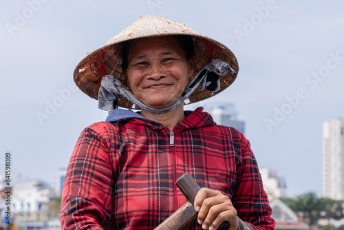 Portrait of an older Vietnamese woman with conical hat, she is looking at the camera while having her picture taken. photo