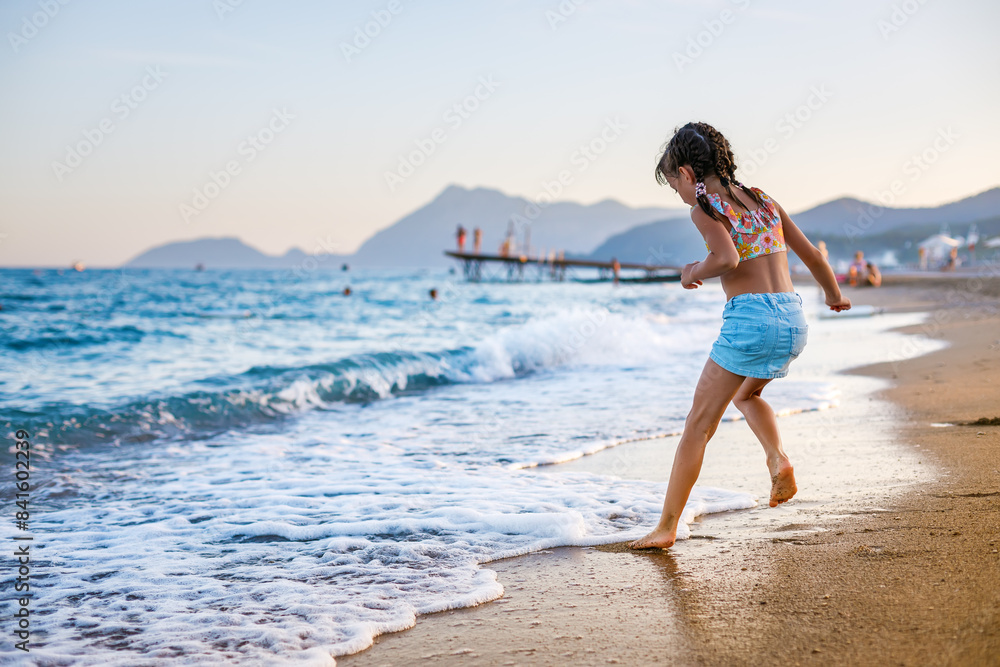 Little girl having fun at the beach, splashing in the water and waves, enjoying a relaxing leisure activity Little girl having fun at the beach, splashing in the water and waves, enjoying a relaxing leisure activity