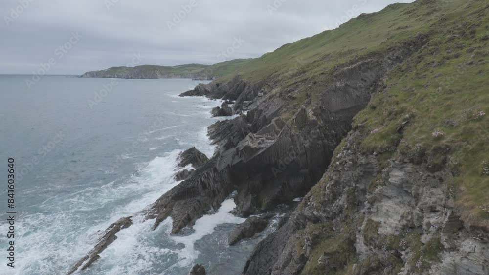 Steep rocky coastline with ocean waves slowly crushing on the rocks. Steep rocky coastline with ocean waves slowly crushing on the rocks.