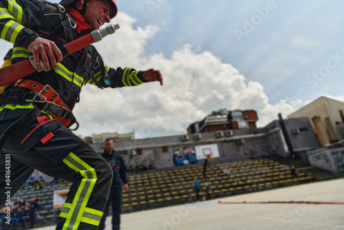 In a dynamic display of synchronized teamwork, firefighters hustle to carry, connect, and deploy firefighting hoses with precision, showcasing their intensive training and readiness for challenging © .shock