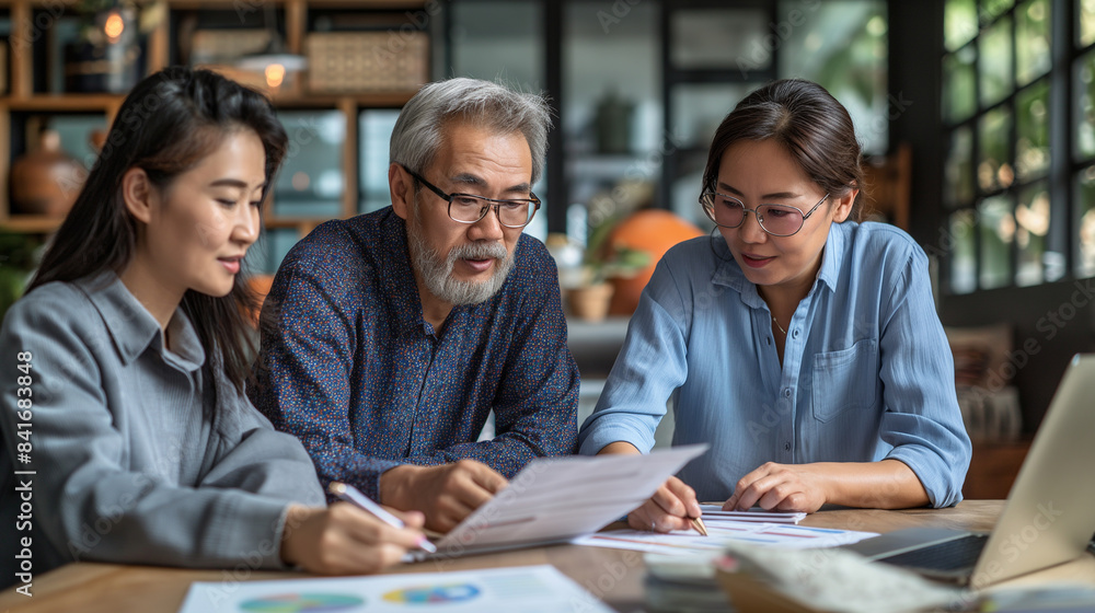 Asian family budgeting together at a table, discussing finances and reviewing documents. Perfect for illustrating family financial planning, teamwork, and money management Asian family budgeting together at a table, discussing finances and reviewing documents. Perfect for illustrating family financial planning, teamwork, and money management