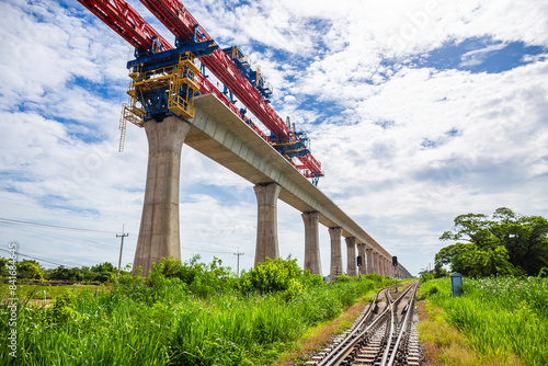 Bild auf Leinwand High-elevation railway construction crane in the Bangkok-Nakhon Ratchasima high-speed rail project with ordinary tracks underneath