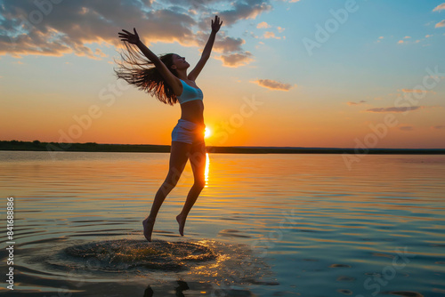 Young woman jumping into the lake in sunset