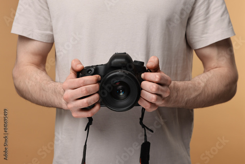 Photographer holding camera on beige background, closeup