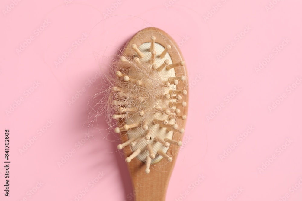 Wooden brush with lost hair on pink background, top view Wooden brush with lost hair on pink background, top view