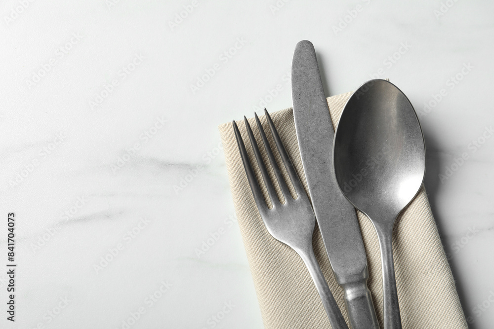 Set of stylish cutlery and napkin on white marble table, top view. Space for text Set of stylish cutlery and napkin on white marble table, top view. Space for text
