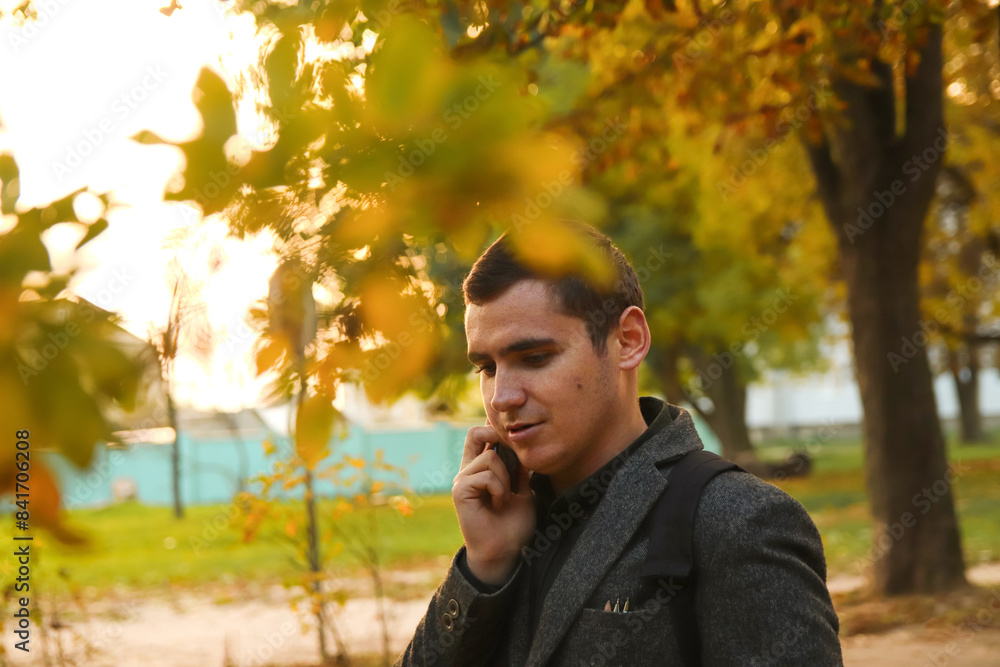 Man talking on the phone outdoors in autumn. Mobile communication: man talking on his phone in a casual autumn scene Man talking on the phone outdoors in autumn. Mobile communication: man talking on his phone in a casual autumn scene