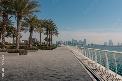 Abu Dhabi cityscape with palm trees and promenade. Landscape view of Abu Dhabi with skyscrapers on the background.