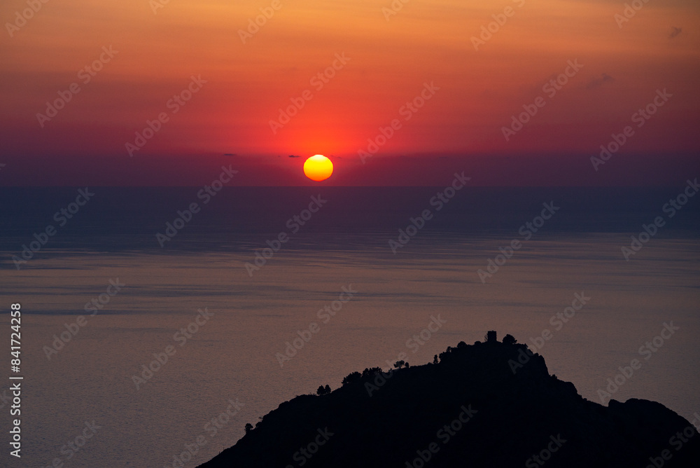 The sunset over the silhouette of Molla de Tuent watch tower in a hill top near Sa Calobra, Majorca, Balearic Islands, Spain The sunset over the silhouette of Molla de Tuent watch tower in a hill top near Sa Calobra, Majorca, Balearic Islands, Spain