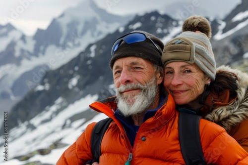Portrait of a blissful couple in their 50s wearing a warm parka over panoramic mountain vista