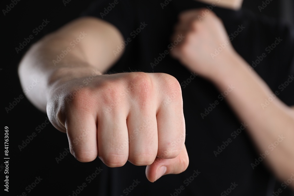 Man showing fist with space for tattoo on black background, selective focus Man showing fist with space for tattoo on black background, selective focus