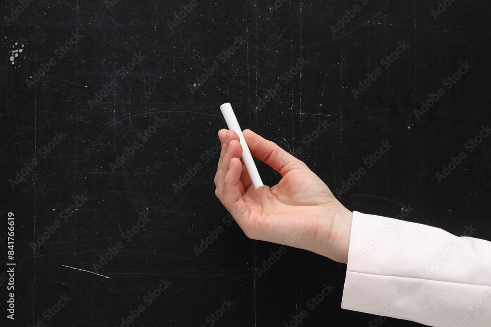 Naklejka premium Teacher writing with chalk on black chalkboard, closeup. Space for text