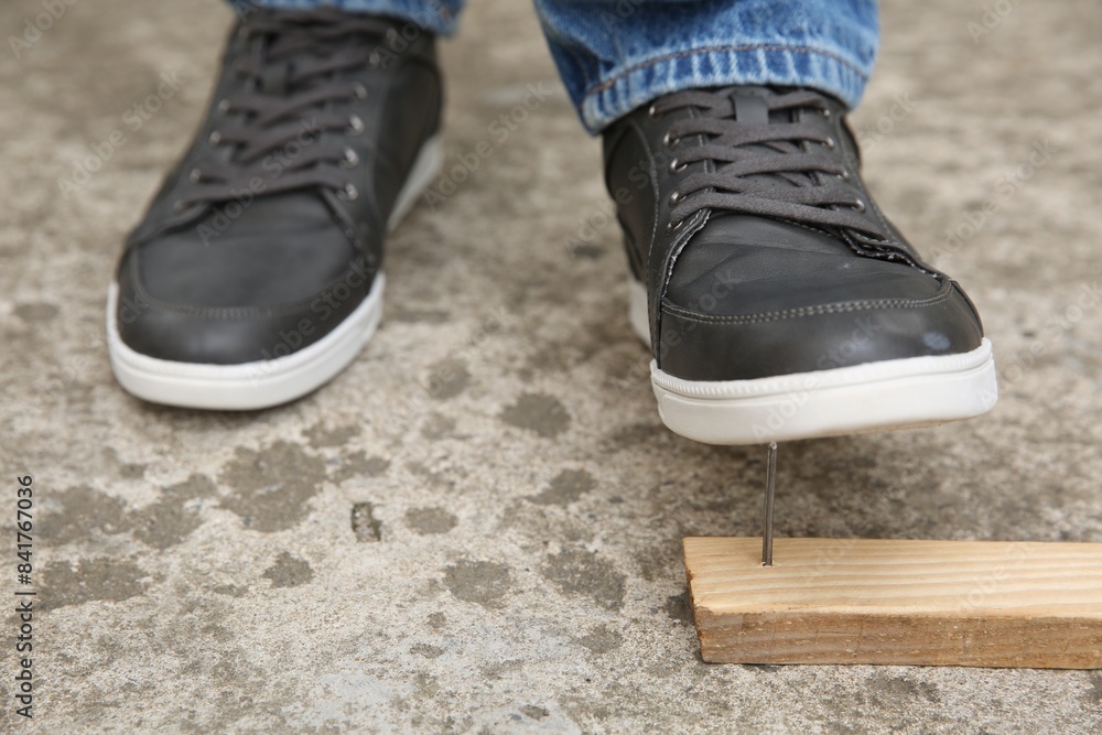 Careless man stepping on nail in wooden plank outdoors, closeup Careless man stepping on nail in wooden plank outdoors, closeup
