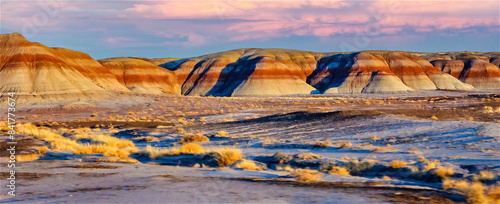 The vibrant hues of sunset illuminate the undulating hills of the painted desert