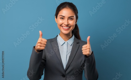 Confident Businesswoman Giving Thumbs Up in Front of Blue Background