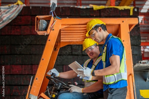 Two warehouse workers operate a forklift in a warehouse photo