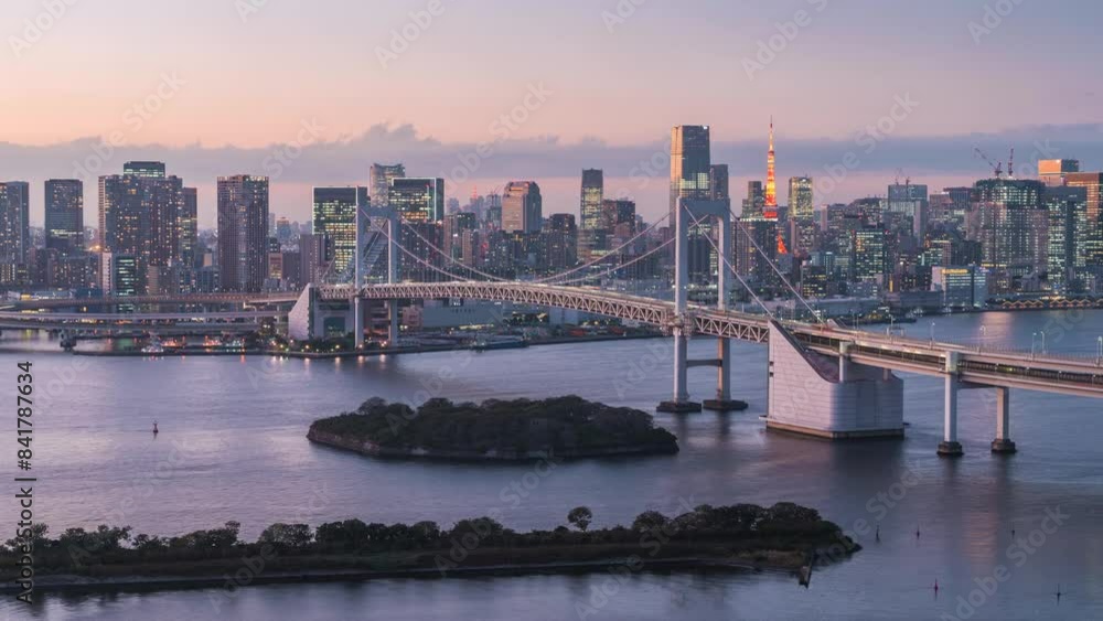 Day to night timelapse view of Tokyo skyline showing Tokyo Bay with architectural landmark Rainbow Bridge in Tokyo, Japan, zoom out. Day to night timelapse view of Tokyo skyline showing Tokyo Bay with architectural landmark Rainbow Bridge in Tokyo, Japan, zoom out.