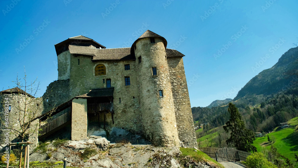 A large stone building with a steeple sits on a hillside A large stone building with a steeple sits on a hillside
