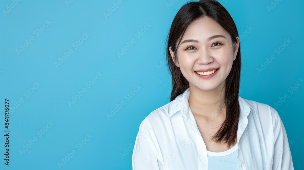 A smiling woman in white stands against a blue background, exuding confidence and warmth. A smiling woman in white stands against a blue background, exuding confidence and warmth.