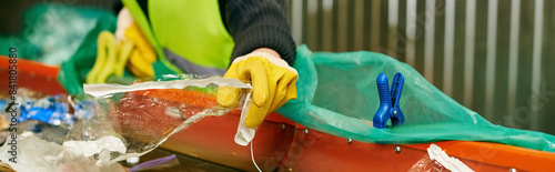 Fotografie A conscientious young volunteer in a green vest and yellow gloves sorts trash with other eco-conscious individuals