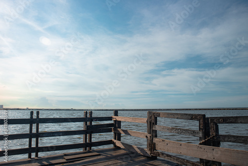 Scenic view of a tranquil waterfront pier under a bright blue sky, capturing the serene beauty of the sea and the peaceful ambiance of a calm day by the water.