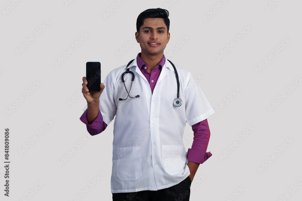 young Indian male doctor with stethoscope on his neck showing smartphone to camera isolated on white background young Indian male doctor with stethoscope on his neck showing smartphone to camera isolated on white background