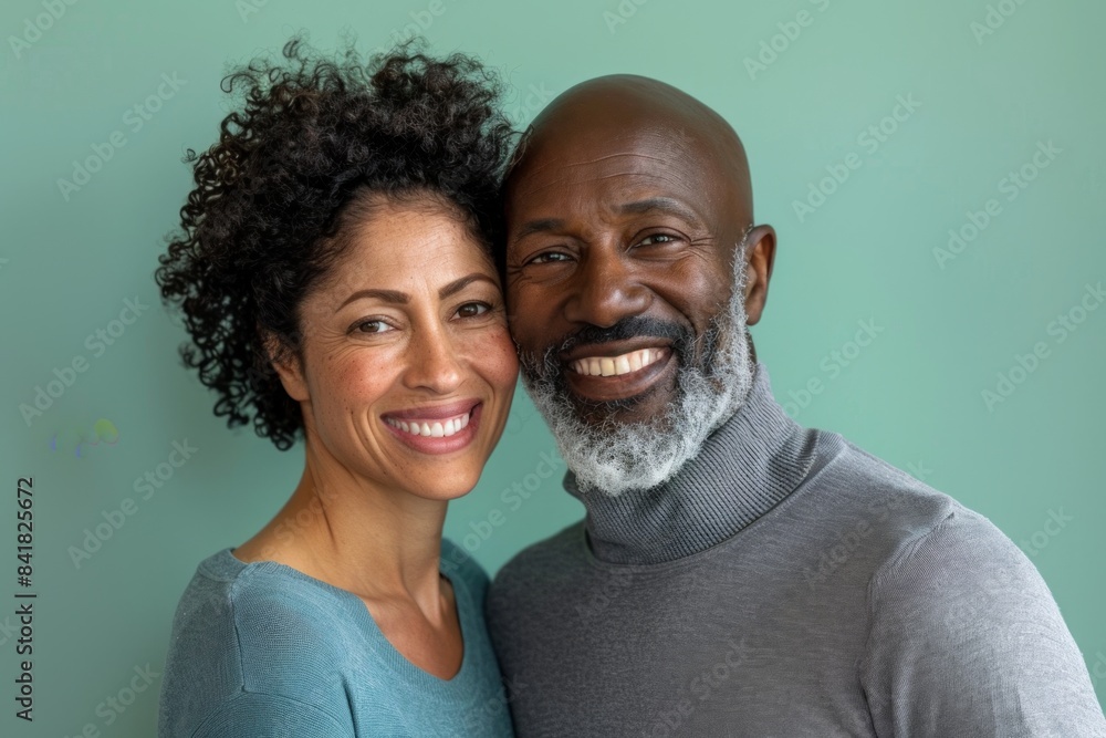 Portrait of a grinning multiethnic couple in their 40s showing off a thermal merino wool top isolated on pastel green background Portrait of a grinning multiethnic couple in their 40s showing off a thermal merino wool top isolated on pastel green background
