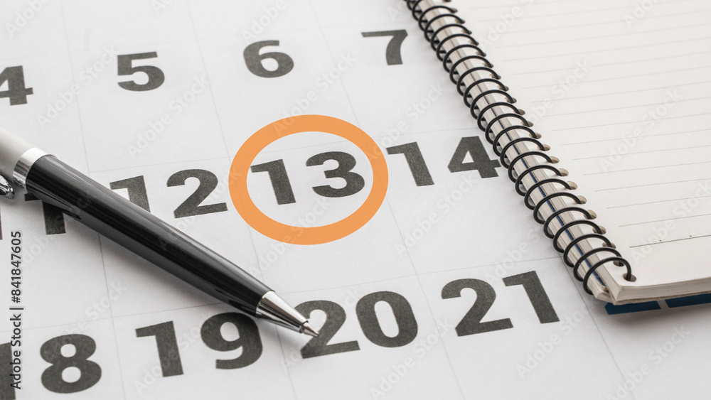calendar with the 13th marked with a red circle. Notebook, calendar and pen on the table calendar with the 13th marked with a red circle. Notebook, calendar and pen on the table