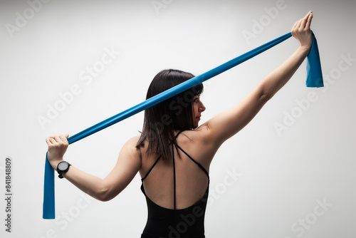 Young woman exercising with resistance band in a studio setting, focusing on fitness and health