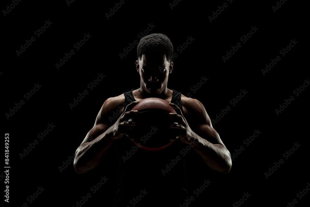 Basketball player holding a ball against black background. Serious concentrated african american man. Basketball player holding a ball against black background. Serious concentrated african american man.