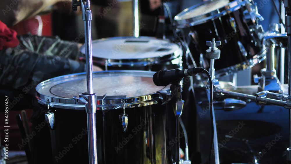 Fototapeta premium A complete drum kit for a single drummer including a variety of drums, cymbals and other percussion instruments. Black drum kit on stage.