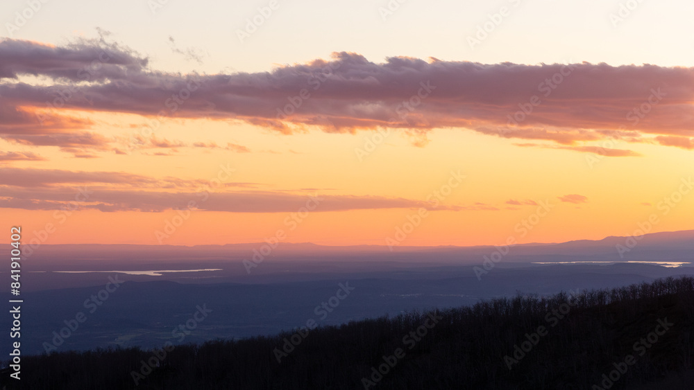 Vivid sunset over a forested landscape with distant lake Vivid sunset over a forested landscape with distant lake
