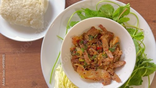 a dish of Nam Tok beef ( spicy grilled beef salad)  and sticky rice.
