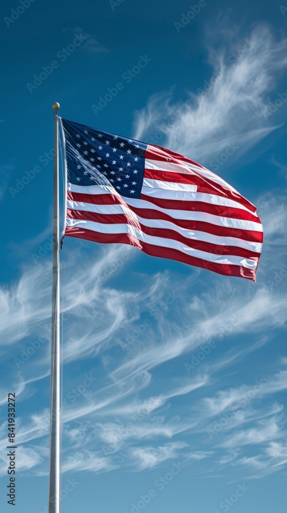 Naklejka premium USA flag on a flagpole against a blue sky