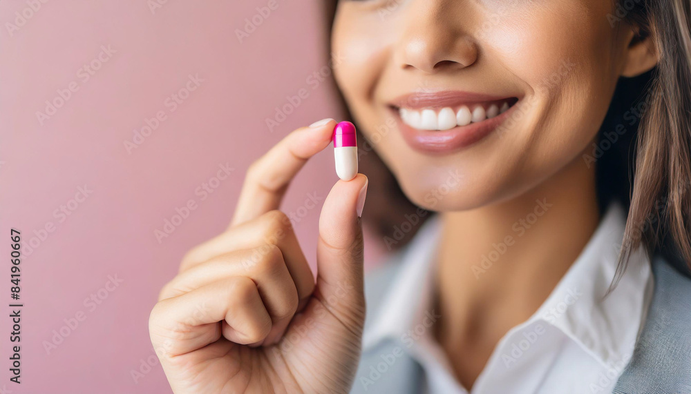 woman's hand delicately pinching pink and white birth control pill, symbolizing autonomy in healthcare choices woman's hand delicately pinching pink and white birth control pill, symbolizing autonomy in healthcare choices