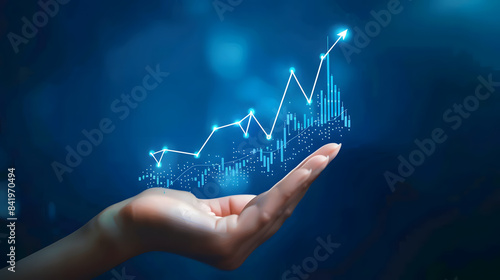 A hand holds a chart with a growing up arrow and a graph of stock market or business growth on a virtual screen 