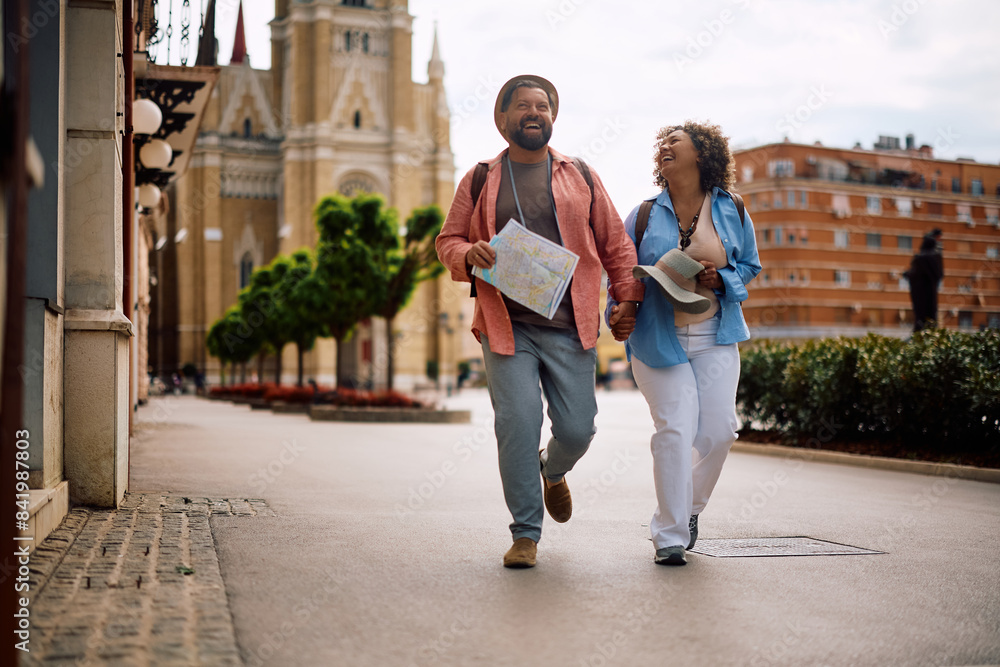 Fototapeta premium Carefree mature couple laughing while sightseeing in city.