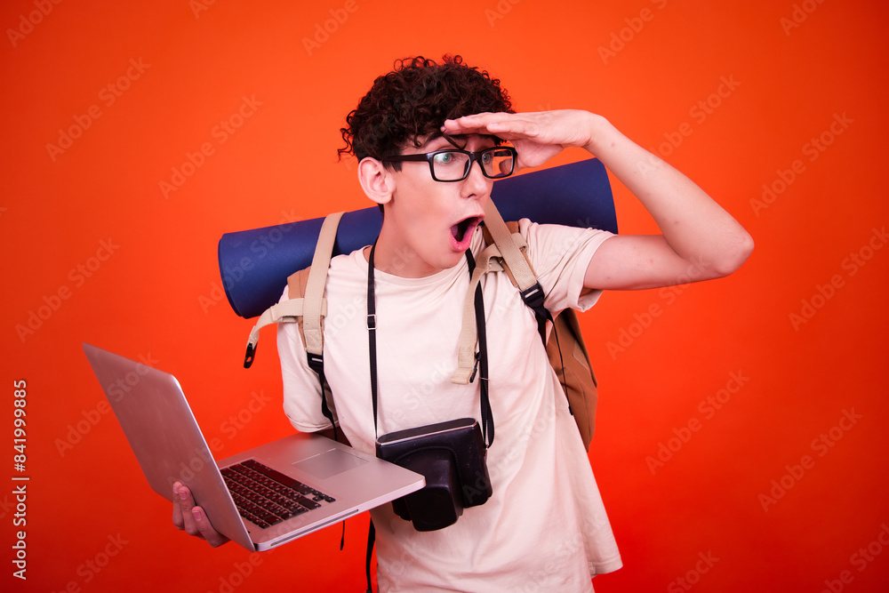 Vacations and holidays. Funny lost tourist with a backpack. Orange background. Vacations and holidays. Funny lost tourist with a backpack. Orange background.