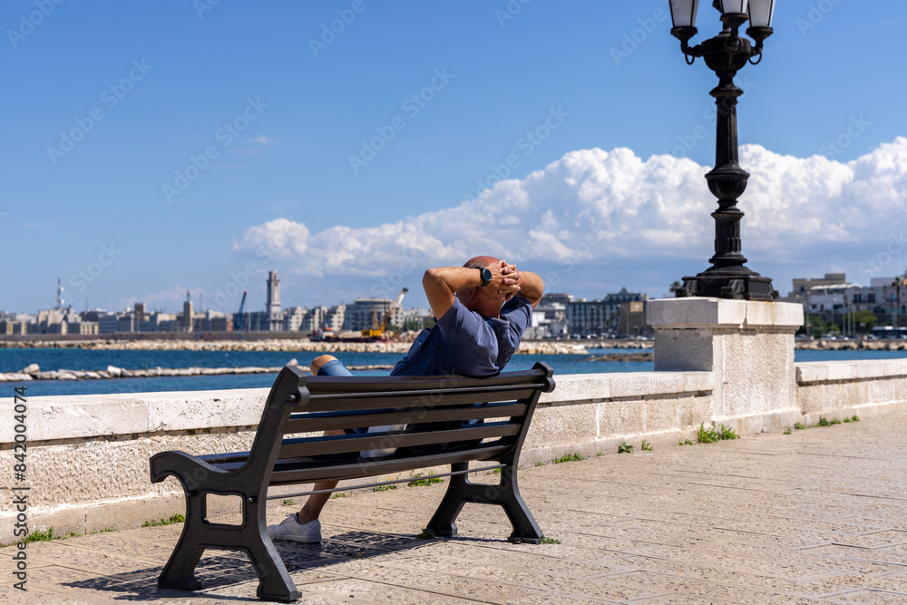 Man resting on a bench at Emperor Augustus seafront (Lungomare Imperatore Augusto), promenade by Adriatic Sea, Bari, Italy, Apulia