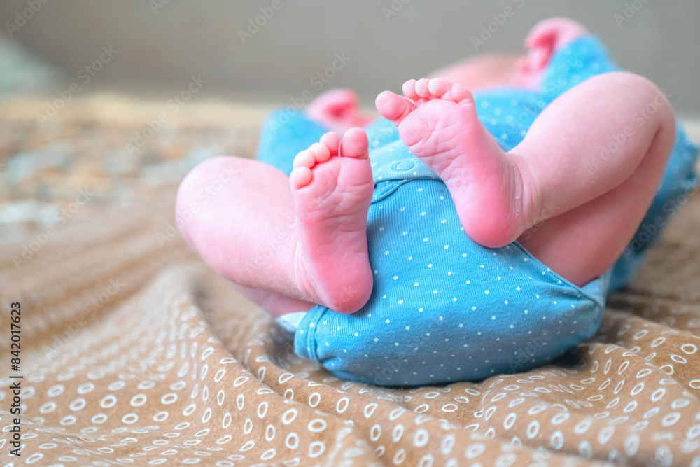 Funny image of happy newborn baby lying on a bed sleeping on brown sheets. Close up soft feet of a new born. Horizontal image. Copy space. Funny image of happy newborn baby lying on a bed sleeping on brown sheets. Close up soft feet of a new born. Horizontal image. Copy space.