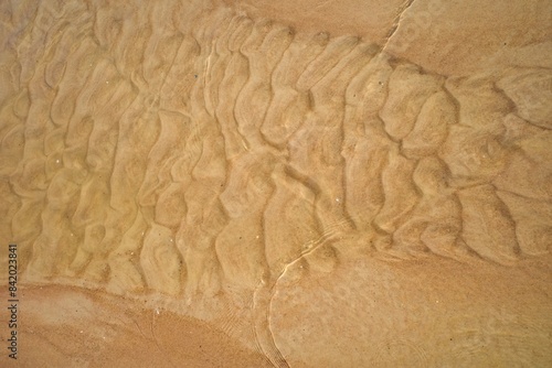 Ocean water texture background. Top view of the sandy seabed. Shallow water surface.